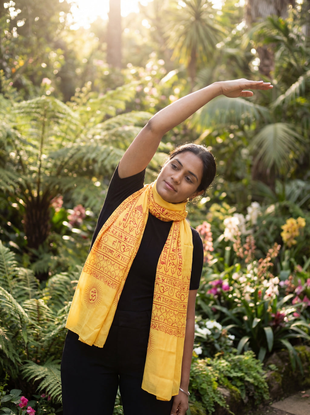 Person wearing a yellow yoga scarf in a lush green garden