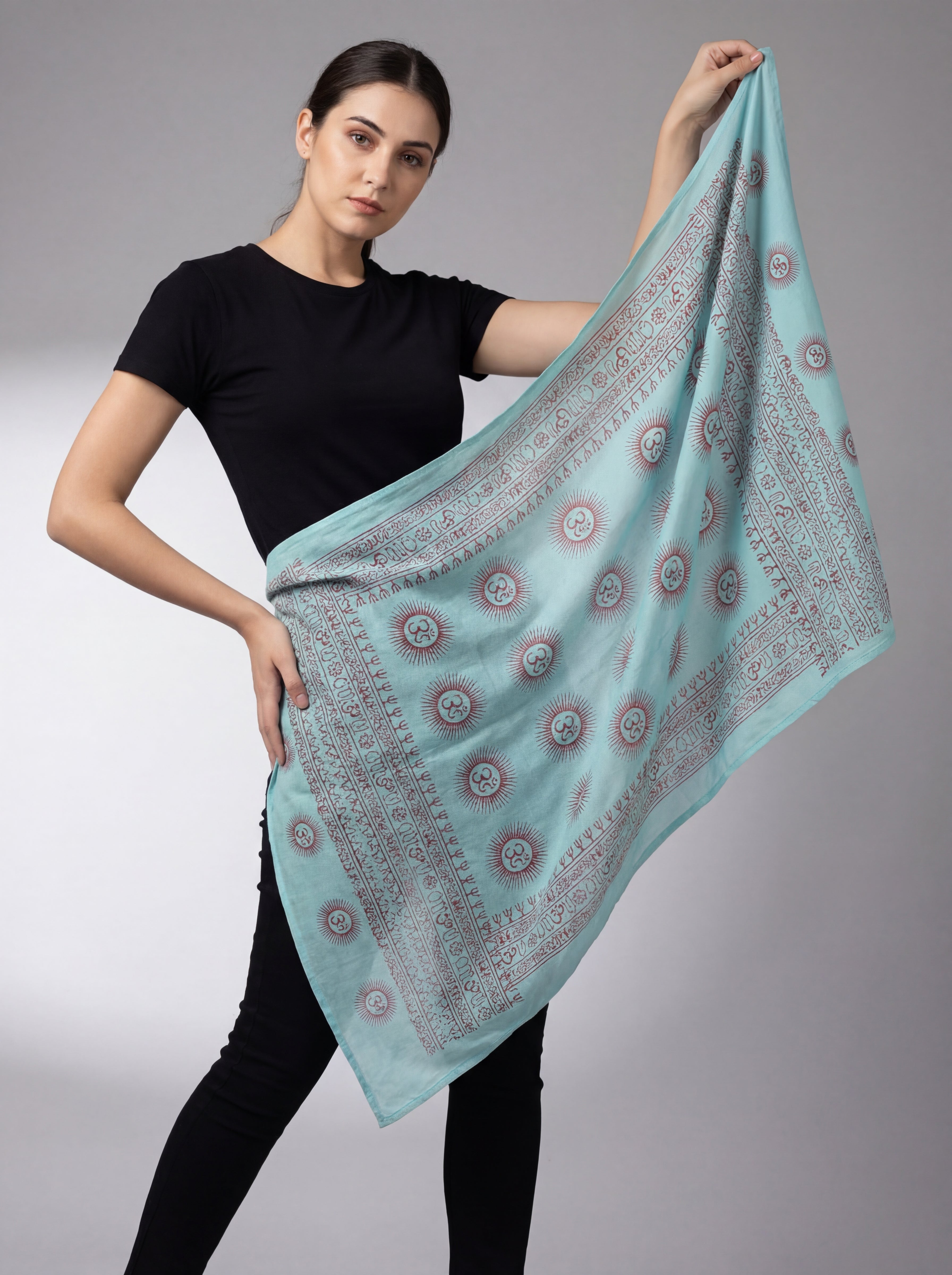 Woman holding a light blue patterned Om yoga scarf against a gray background