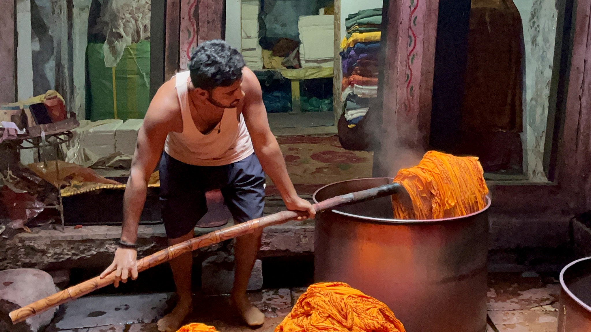 Man using traditional method of dyeing fabric orange for our yoga scarves 