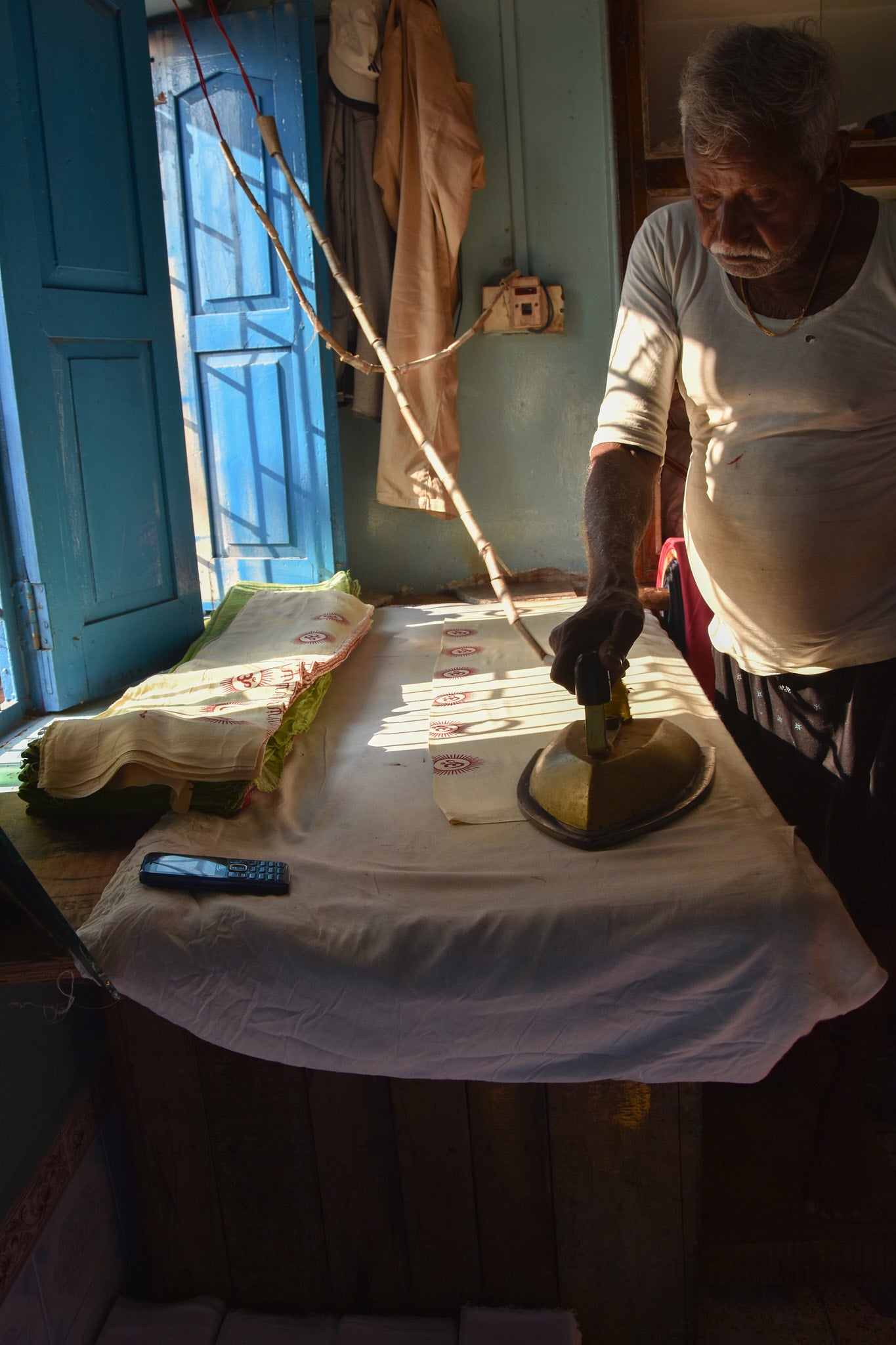 Man ironing Om pattern yoga scarf on a table 